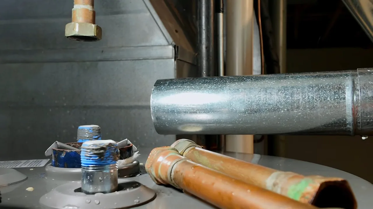 Galvanized vent pipe and copper supply lines above the top of a water heater.